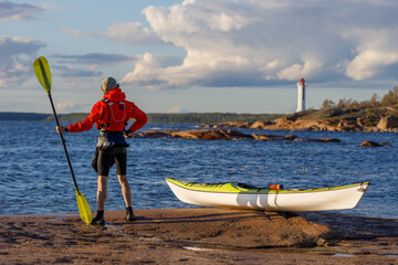Man with a kayak outdoors. The background of the evening sea is blurred.