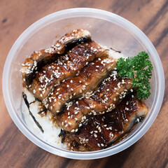 Unagi don sprinkled with sesame in a plastic bowl. Food delivery.