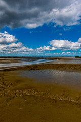 View of the Lower Saxony Wadden Sea at low tide in summer with blue sky and beautiful clouds