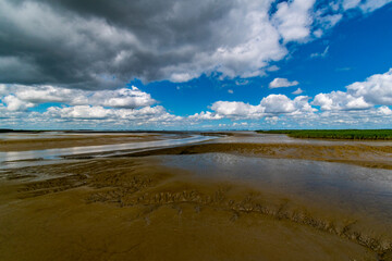 Fototapeta na wymiar View of the Lower Saxony Wadden Sea at low tide in summer with blue sky and beautiful clouds
