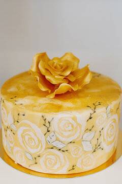 Elegant wedding cake with a large royal icing rose on top dripped in gold edible paint and encircled by floral watercolor print on fondant, a spectacular dessert ready for a wedding or a special event