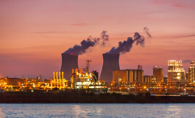 Cooling towers of a nuclear reactor power generating facility are silhouetted against a brilliant...