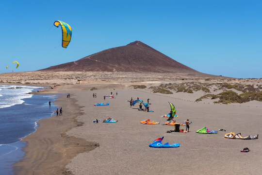 Montana Roja beach side with surfers enjoying a windy day practicing water sports such as kite surfing or kite boarding at El Medano, Tenerife, Canary Islands, Spain