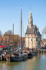 Fototapeta premium Hoorn, Netherlands; Boats tied up in a port facility in Hoorn, Netherlands. The port building has a clock tower.