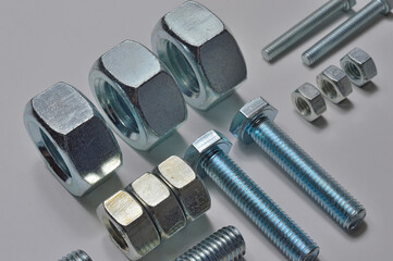 bolts and nuts of different sizes are laid out on a light background.