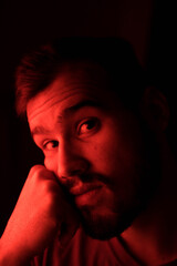 Selective focus portrait of young caucasian man with red light on his face
