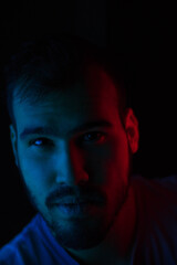 Selective focus portrait of young caucasian man with blue and red lights on his face