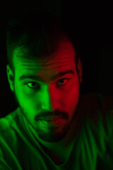 Selective focus portrait of young caucasian man with green and red lights on his face