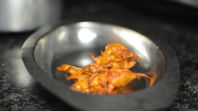 Close up shot of Indian pakoras or onion bhajis stacked in a stainless steel plate