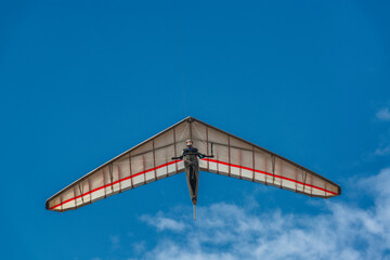 Bright hang glider wing silhouette from below.