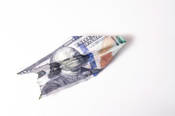 Burnt dollars. Burnt side view on a white background banknotes in close-up. Dollars in the form of a paper airplane on a white background