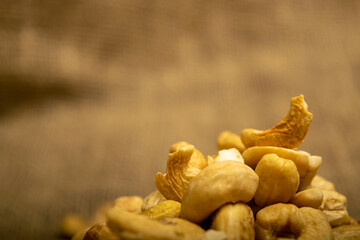 A pile of cashew nuts on burlap with a rough texture surface texture. Close up.