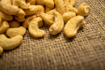 A pile of cashew nuts on burlap with a rough texture surface texture. Close up.