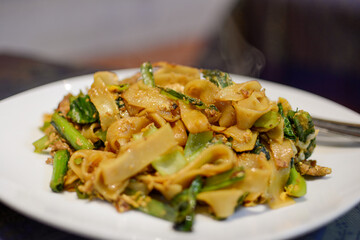 タイ王国の代表的な麺料理、パッタイ。米の太麺の焼きそば。青菜入り。太麺。米粉麺。