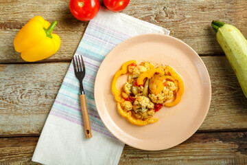 Vegetable stew on a beige plate on a napkin with a fork on a wooden table Nearby vegetables.