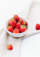Fresh strawberries in white bowl on linen napkin