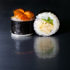 Rolls wrapped in seaweed with a reflection of rice, cucumber, omelet and fruit in a sweet sauce
