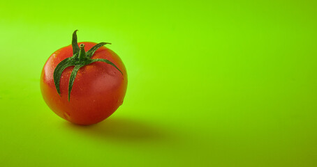 a fresh tomato with green leaves on a green background