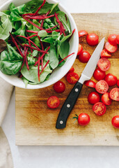 Green salad, cherry tomatoes on wooden board and knife
