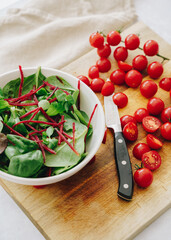 Green salad, cherry tomatoes on wooden board and knife
