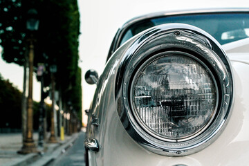 Phare de voiture de collection de couleur blanche dans une rue de Paris près des Champs Elysées lors d'un couché de soleil