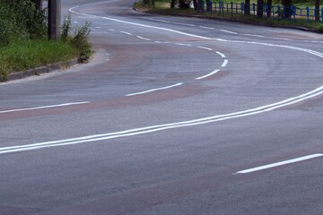 empty winding paved road with a marking of traffic lanes