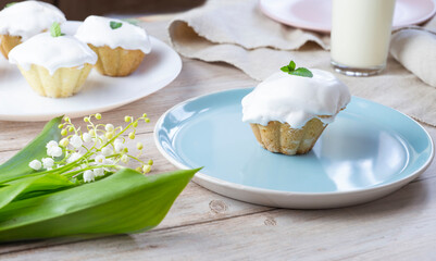 Cupcake with white cream in a plate. Nearby lies a bouquet of lilies of the valley