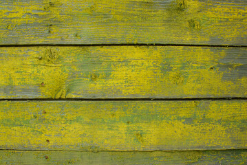 Old tumbledown weathered wood boards background with peeled yellow paint, shabby rustic gray barn timbered siding aged withered faded flooring surface. Obsolete blank abstract rustic rundown wall.
