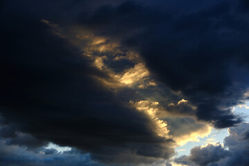 Naklejka na ściany i meble Storm clouds with breaking rays of sunlight.