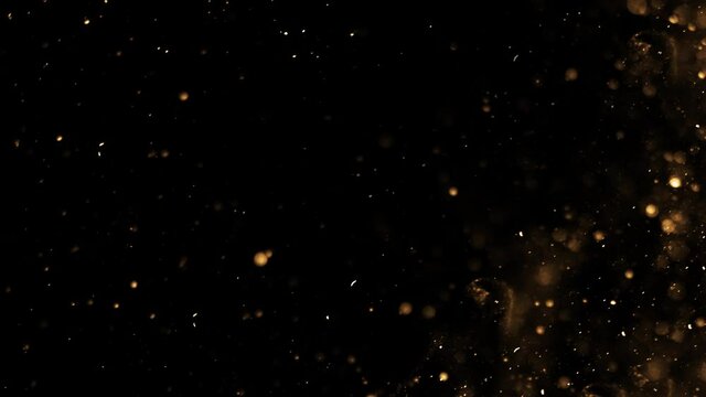 Gold dust particles fly in slow motion in the air lingering slowly. Dust Particles Background Bokeh Lights Background on Black Background 4k Footage Snow Particles Background.