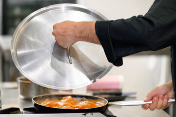 Close up, chef covering frying pan with lid at restaurant kitchen. High quality photo.