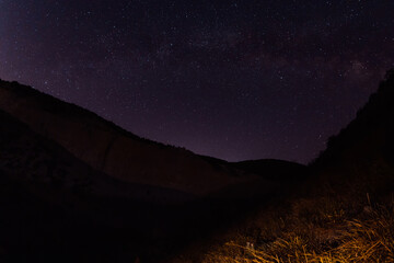Fototapeta na wymiar Night star sky with Milky way galaxy and canyon with mountains