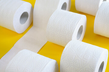 Rolls of new toilet paper lie on a yellow background