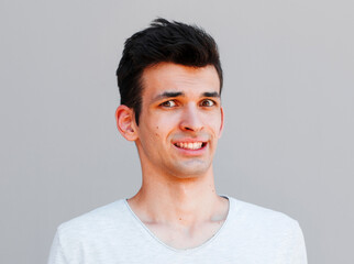 Fototapeta premium Indoor shot of puzzled and confused man showing teeth while looking at camera and standing over gray background. Husband forgot to throw garbage and now says sorry