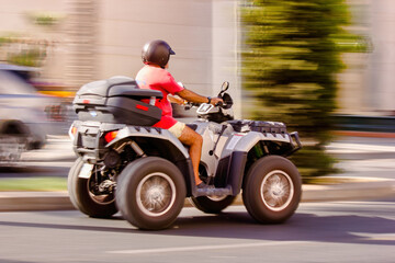 Obraz na płótnie Canvas Malaga, Spain - September 04, 2015: Side view of a man wearing helmet and riding quadro four wheel scooter aka quooder in costa del sol