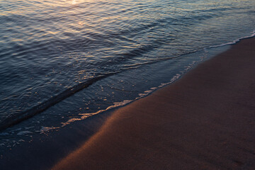 sunrise on the sandy beach with sunbeam reflection in the dark, blue water