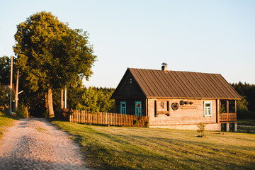 Old wooden house in village. National wooden farmhouse in Belarus. View of rustic ethnic house on sunset. Rural landscape 