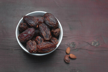 Dates, dry fruits in a plate on a wooden table, sprout of nuts