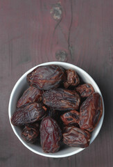Dates, dry fruits in a plate on a wooden table