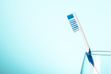 Toothbrush in a glass. Blue bathroom wall with copy space. Concept for dental clinic. Object photography.