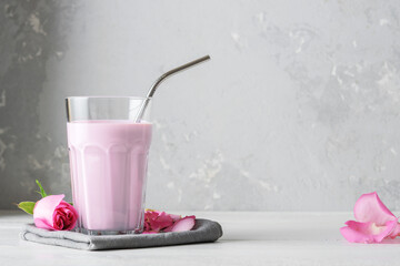 A glass of moon milk with a rose on a white table. Ayurvedic relaxing drink for the night.