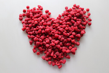 Obraz premium Fresh raspberries in the shape of a heart on a white background