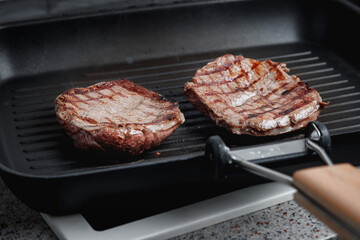 A large piece of fresh beef meat cooked in a grill pan. Stripes on the meat. Fluted frying pan.