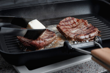 A large piece of fresh beef meat cooked in a grill pan. Meat is fried in butter. Stripes on the meat. Fluted frying pan.