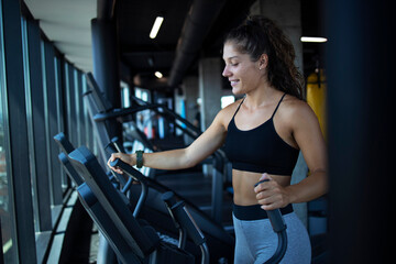 Fototapeta na wymiar Sportswoman or athlete smiling on training while running on treadmill machine in the gym. Happy and positive people workout.