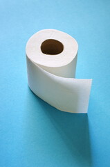 Roll of toilet paper on the blue background. Tissue for use in the toilet room, used for cleaning the dirt in the bathroom. People are stocking up toilet paper for home quarantine from coronavirus.