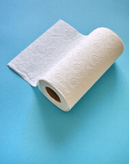Paper towel roll on blue background. Cleaning and wiping kitchen surface with paper towel.