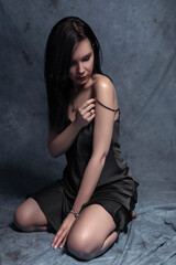 Naklejka premium Brunette slim woman in sexy outfit on a neutral background. Studio portrait in seductive poses