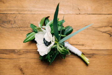 A budier with a white flower on a wooden texture.