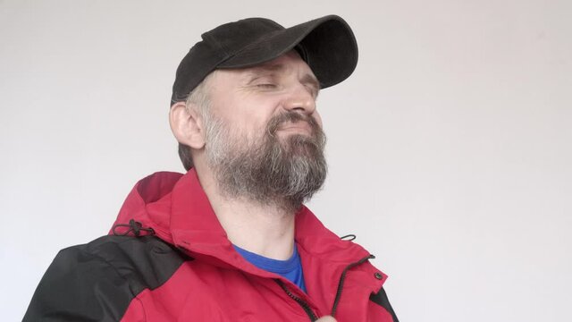 Man in red coat and balck cap smiles and puts on classes.